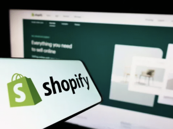 Shopify logo on smartphone with Shopify website in background